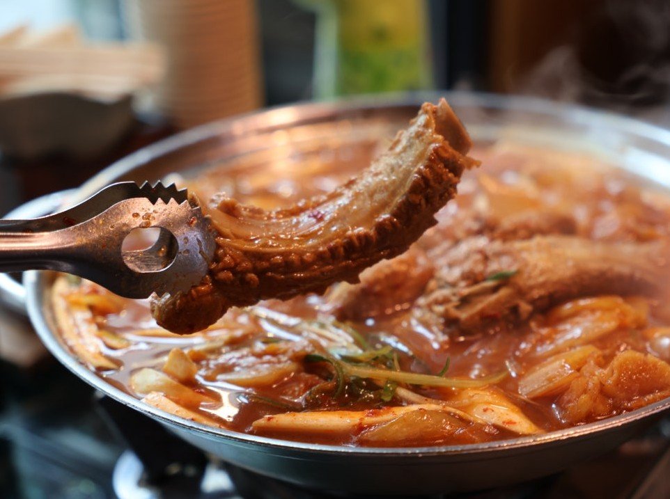 Boiling pot of aged kimchi pork rib stew on tabletop burner at Hwangnam Ddukkeobi Sikdang
